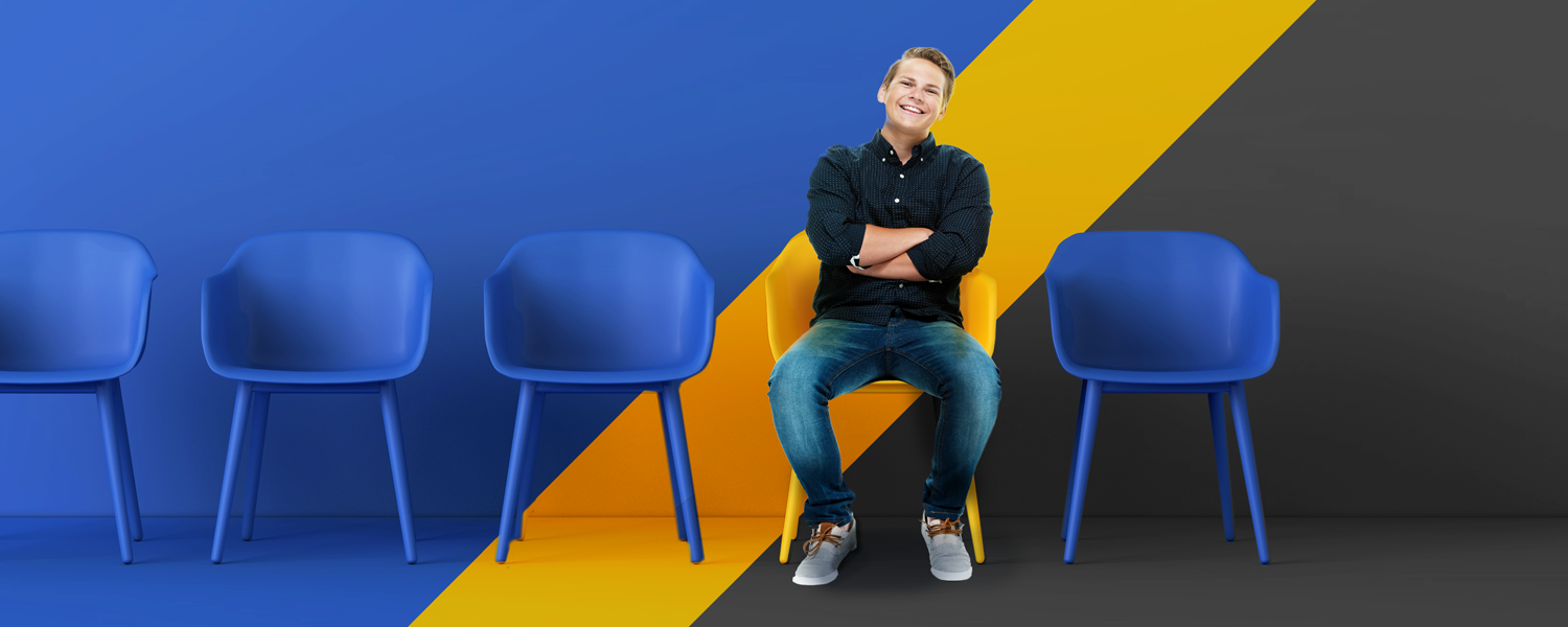 Image of a student sitting on a yellow chair - the rest of the chairs are blue.
