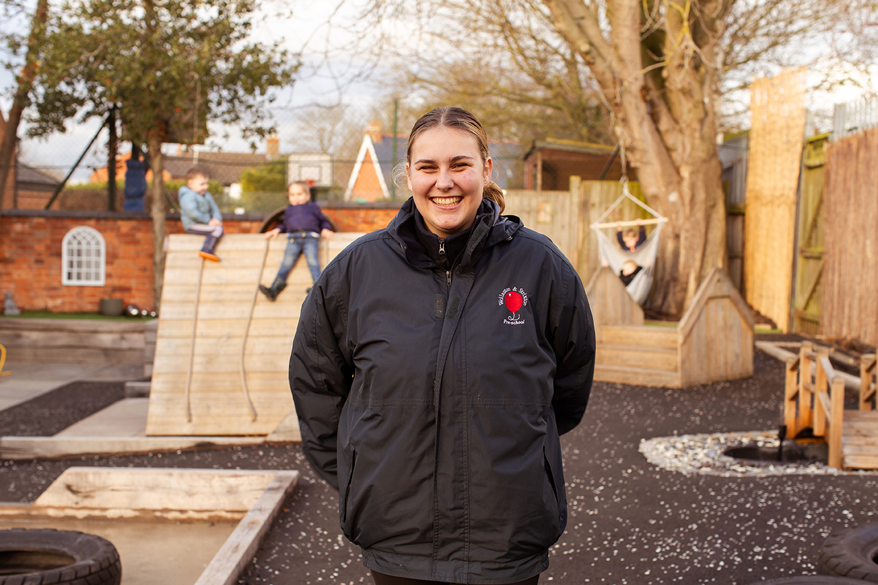 Girl stood in front of children in a boat. 