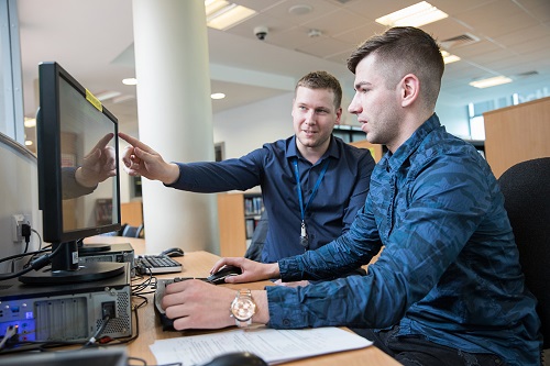 A student and teacher working together on a desktop computer