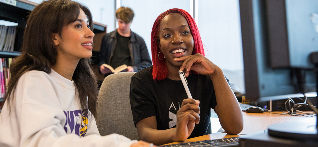 Students smiling as they work in the College Library.