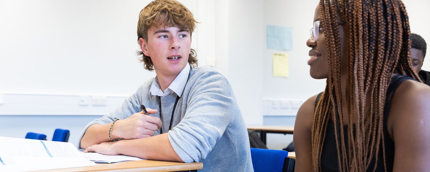 Students smiling as they work in the classroom.