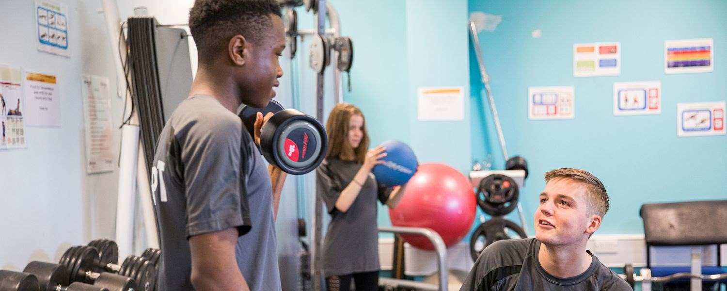 Two male students exercise in the College gym.