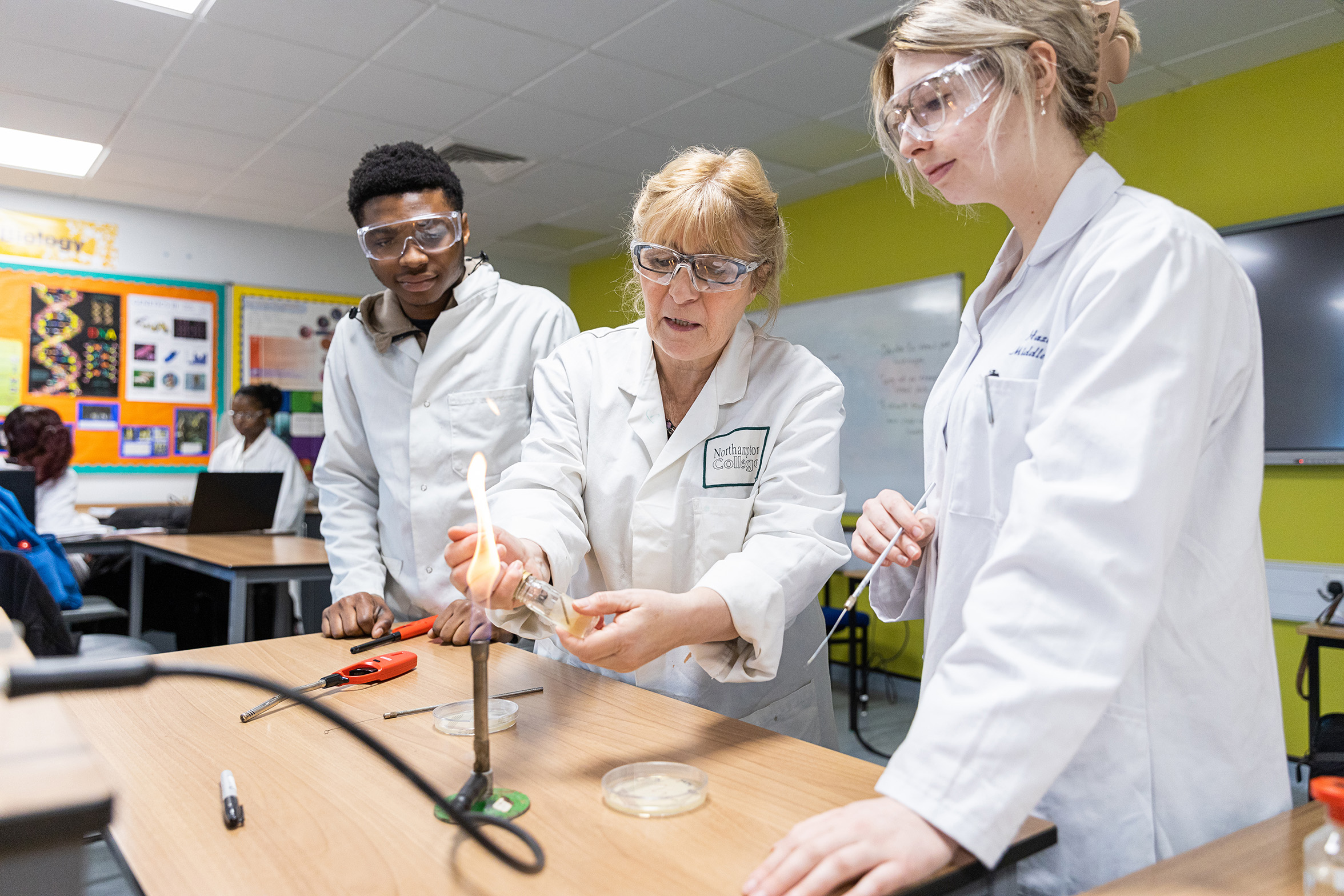 Teacher and students stood in lab coats with a flame. 