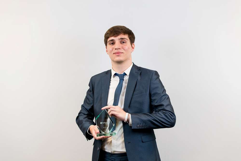 Photo of Adam holding a trophy at the awards ceremony.