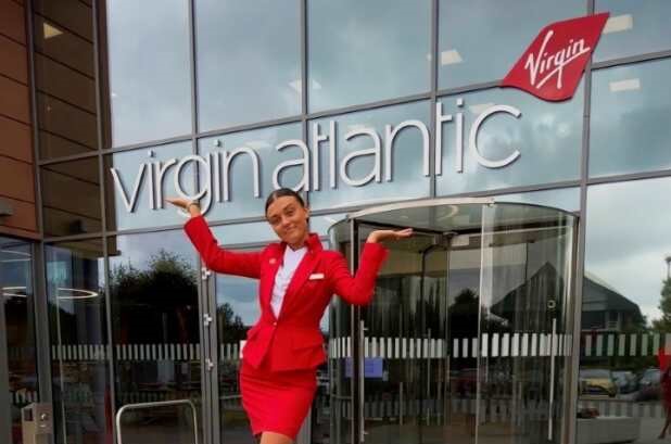 Photo of Hannah posing outside of Virgin Atlantic headquarters in her cabin crew uniform, smiling.