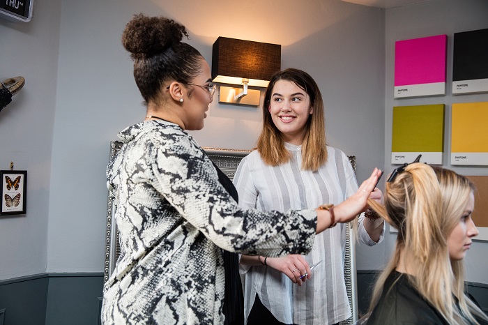 Image of a hairdressing apprentices working on a client with help from their employer.