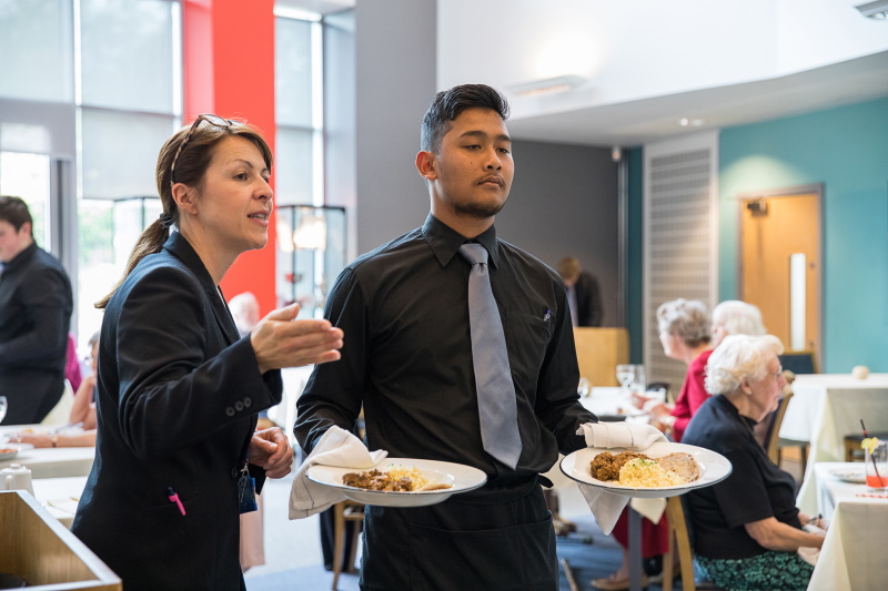 Student waiter delivering meals at The Lane.