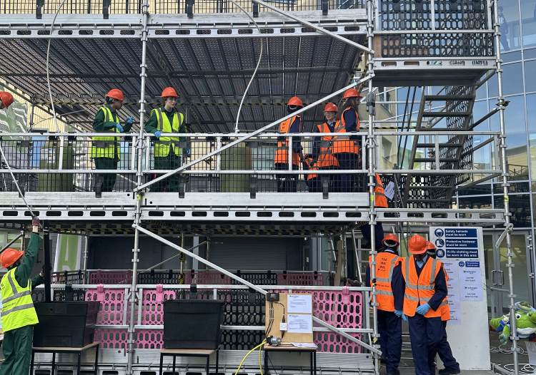Photo shows students in hi vis working on scaffolding structure.