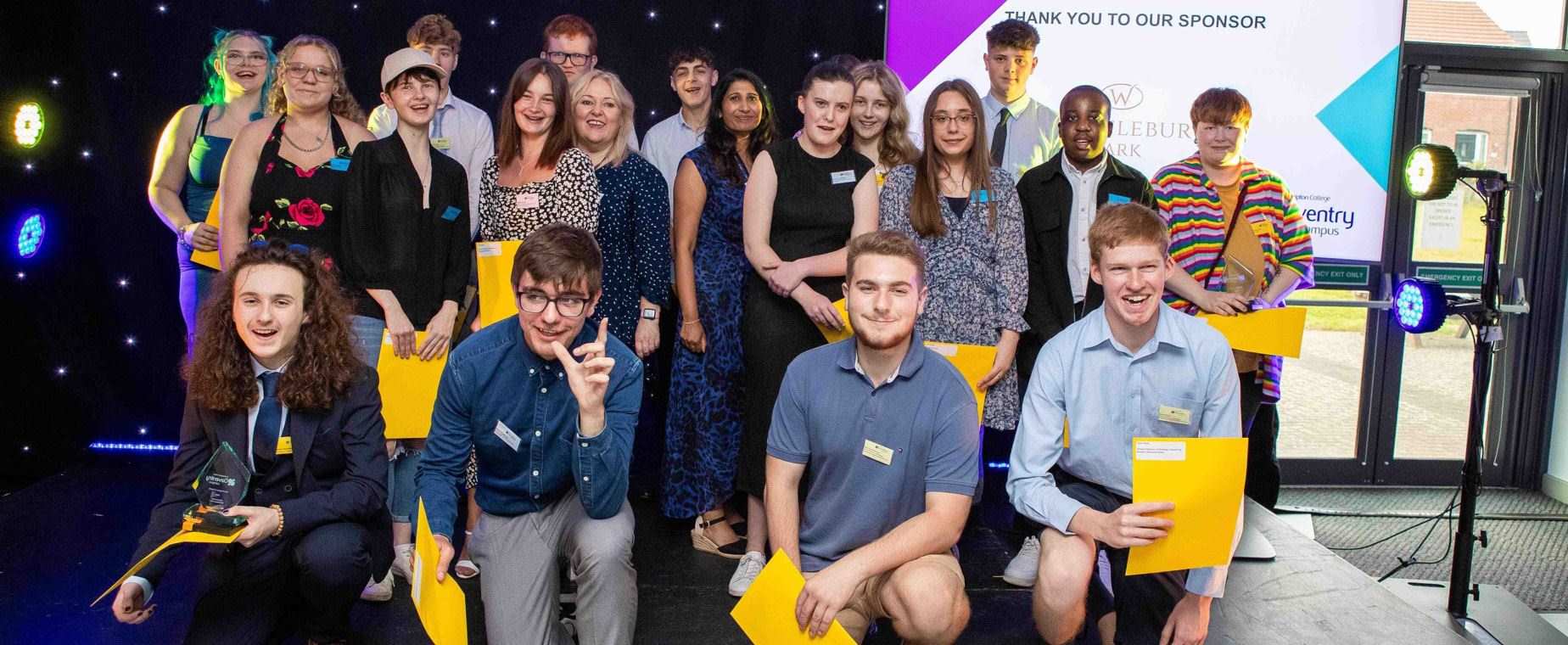 Student award winners pose on stage at awards ceremony.