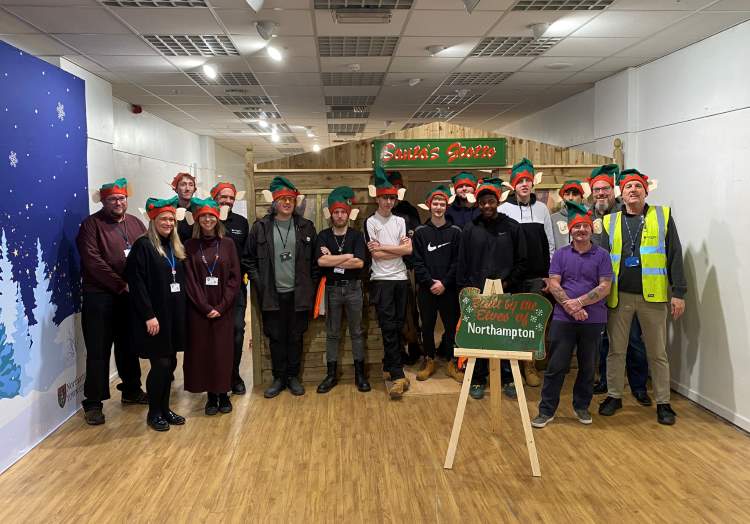 Image shows Construction students and staff posing in a group, next to a grotto.