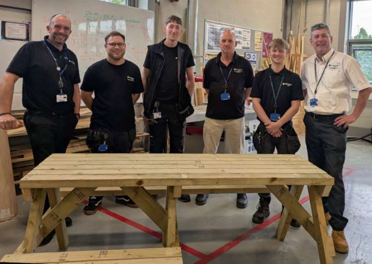 Left: Mark Bradshaw poses staff who worked on the project, and one of the benches they made.