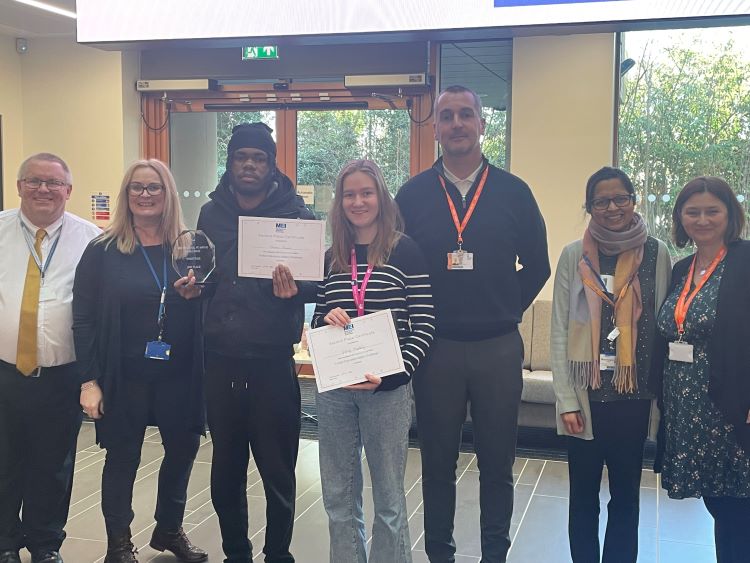 Photo shows the winners posing with a certificate and trophy