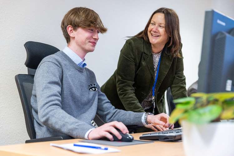 Photo shows accounting student receiving advice from a mentor while working.