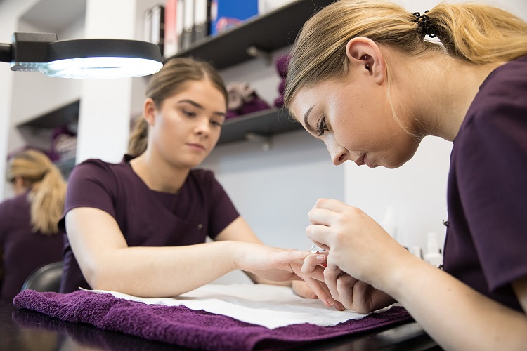 A Beauty Therapy student paints a client's nails.