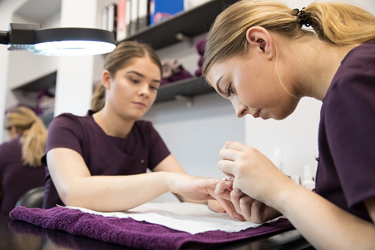 A Beauty Therapy student paints a client's nails.
