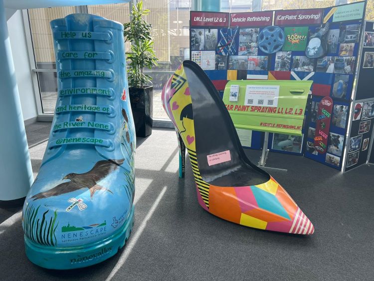 Image shows two large art installations of shoes. One is a blue boot and one is a multicoloured stiletto heel.