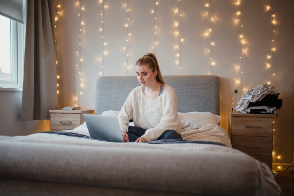 Student in her bedroom sat on a laptop