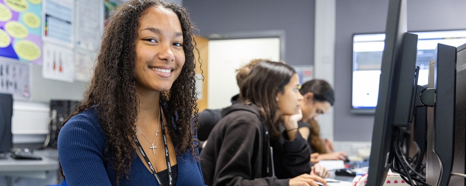 Image shows young student sat at a computer.