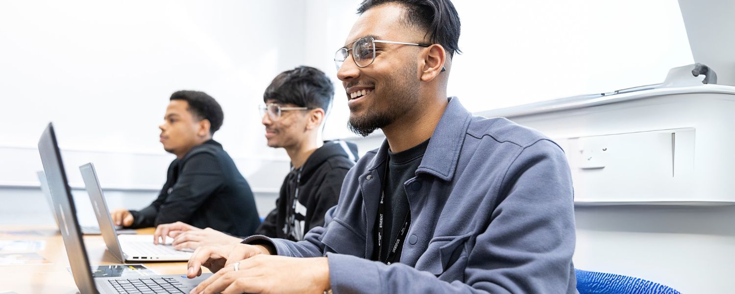 A group of students sitting in a classroom together, each working on laptops.