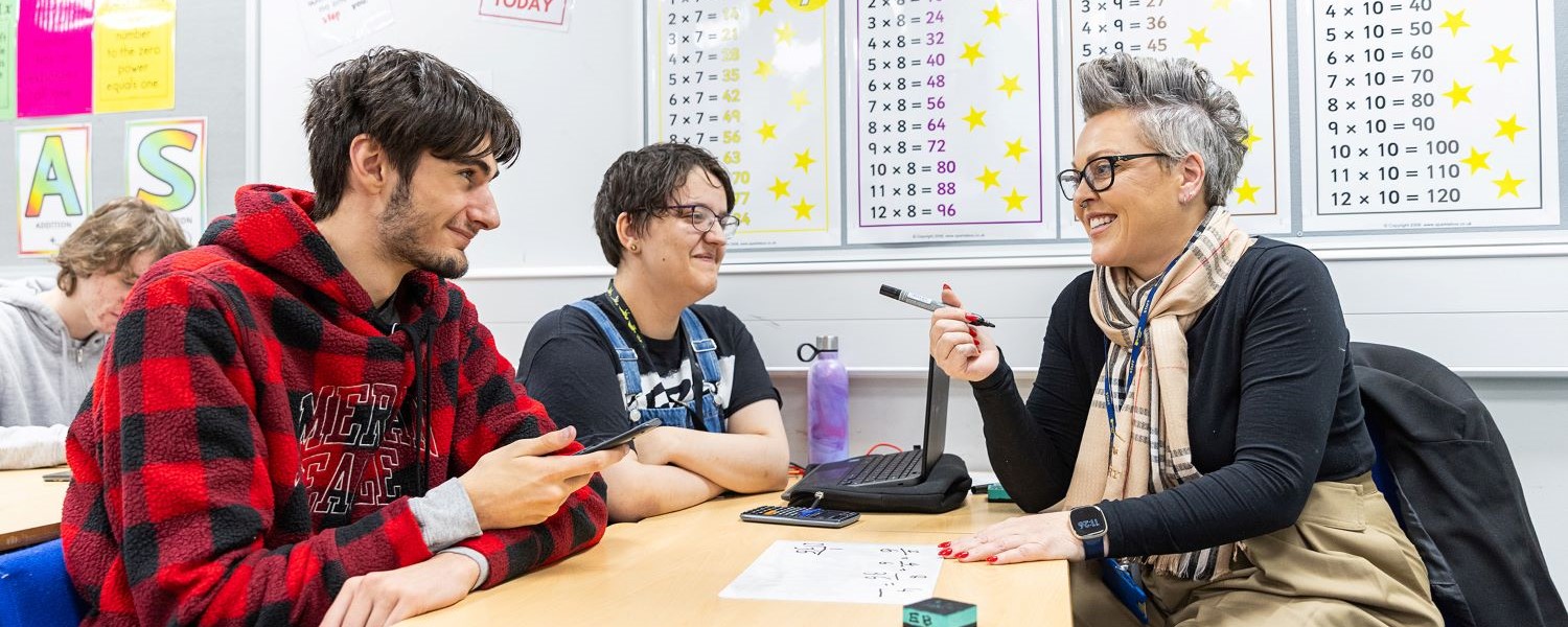 Two students sat with teacher smiling